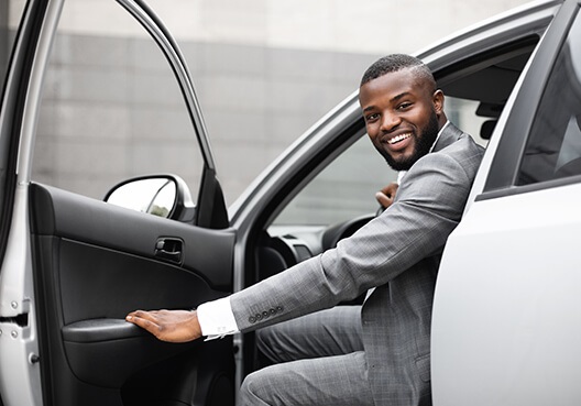 A customer opening his car door and leaning out to smile with his hand on the door handle