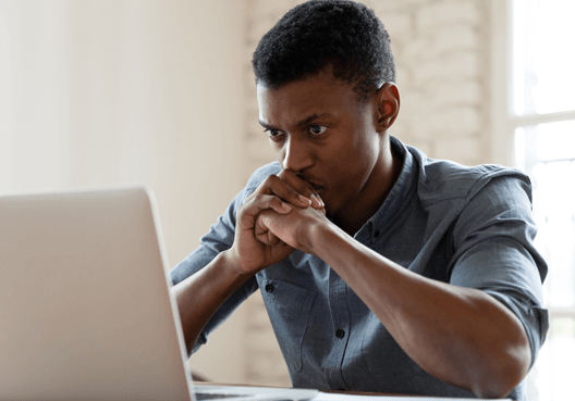 A stressed out man looking at his laptop