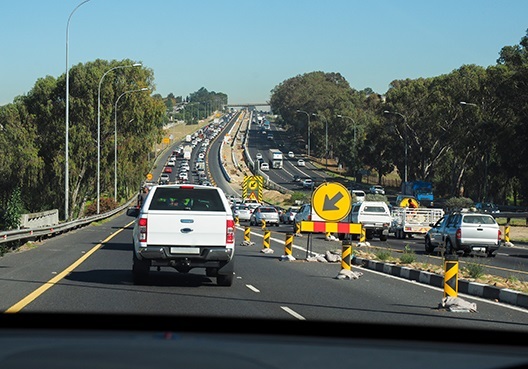 Cars in the road driving cautiously and following the safety signs on the road due to an accident ahead